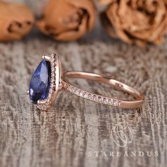 a tan gold ring with a blue stone surrounded by white diamonds on a wooden surface