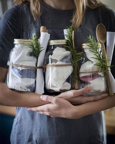 a woman holding jars filled with salt and herbs