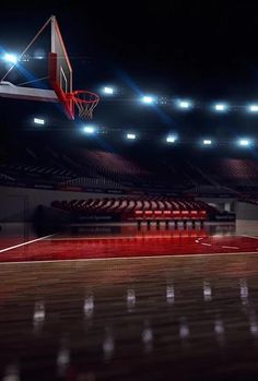 an empty basketball court with the lights on