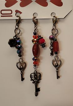 three key chains hanging from the side of a wall with hearts and keys attached to them