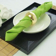 a white plate topped with a green napkin next to a gold ball on top of it