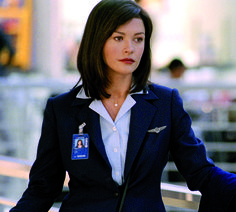 a woman in a blue jacket and white shirt standing next to a metal railing with her hands on her hips