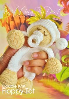 a hand holding a small teddy bear in a knitted outfit with the caption knitting by post double knit happy tot