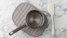 an empty frying pan and spatula on a marble surface