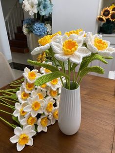 a white vase filled with yellow and white flowers