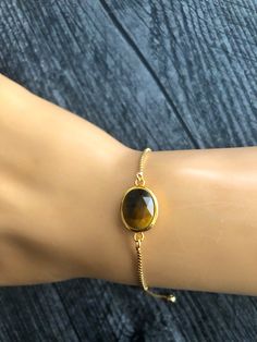 Shop Gold Tiger Eye Bracelet for Women. This dainty bolo bracelet will be a great addition to your everyday or special occasion dress! It will make a great gift for BFF, girlfriend. Brown natural gemstone bracelet is made from: - Faceted Tiger's Eye gemstone connector - Gold plated brass box chain - Gold plated stopper bead The bracelet is 9" long. Brown stone dainty bracelet is fully adjustable- it's easy to put on and take off by yourself- just slide a stopper bead. It will make a great gift! Tiger Stone Bracelet, Tiger Eye Bracelet For Women, Adjustable Oval Bracelets As Gift, Adjustable Oval Bracelet For Gift, Adjustable Oval Dainty Bracelets, Dainty Oval Adjustable Bracelets, Oval Bracelet With Adjustable Chain As A Gift, Gift For Bff, Gold Tiger