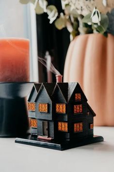 a house model sitting on top of a table next to a candle