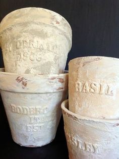 three cement pots sitting next to each other on a black tableclothed surface with the words basil written on them