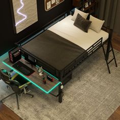 a bed sitting on top of a wooden floor next to a desk with a laptop