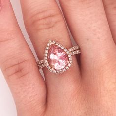 a woman's hand with a pink diamond ring on top of her finger,