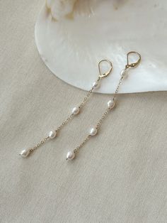 "These beautiful Pearl drop earrings are dainty and elegant. Each of the lustrous organic baroque pearls are hand wrapped in 14K Gold Filled or 925 Sterling Silver. The leverback is secure and stays in place all day! These earrings have beautiful movement and the dainty and durable chain adds a hint of sparkle! Choose from 2 different earring lengths! * 6mm round to oval Baroque Pearls * 14K Gold Filled or 925 Sterling accents * 3 Pearl Length - 2.75\" 4 Pearl Length - 3.75\" * Made with all hyp Delicate Linear Earrings With Ear Wire For Formal Events, Delicate Linear Earrings With Ear Wire For Formal Occasions, Elegant Chandelier Earrings In 14k Gold Filled, 14k Gold-filled Teardrop Linear Earrings For Weddings, Teardrop 14k Gold Filled Linear Earrings For Wedding, Delicate Long Drop Earrings For Formal Occasions, Dainty Drop Pearl Earrings With Lever Back, Delicate Linear Earrings With Ear Wire For Anniversary, Graceful Dangle Earrings For Anniversary