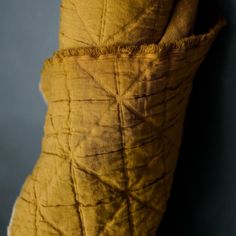 an old yellow pillow is hanging on the wall with a blue back ground behind it