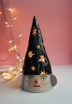 a black hat with gold stars on it sitting next to a string of christmas lights