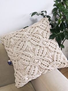 a crocheted pillow sitting on top of a couch next to a potted plant