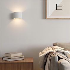 a white wall light mounted on the side of a wall next to a couch and table