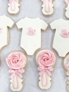 baby shower cookies decorated with pink icing and bows are arranged in the shape of babies'bodysuits