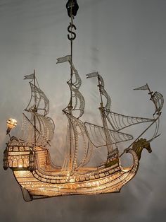 a light hanging from the side of a ship shaped like a boat with sails and lights on it