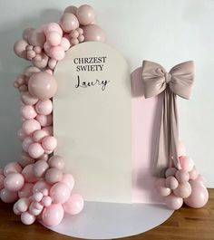 a white sign with pink balloons and a bow on it next to a plaque that says craziest sweety january