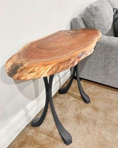 a wooden table sitting on top of a carpeted floor next to a gray couch