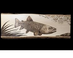 a fish is painted on the side of a piece of wood that has been carved into it