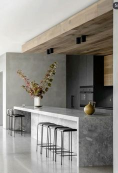 a modern kitchen with marble counter tops and stools