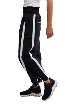 Traditionally sporty track attire gets a street-style reset in these water-resistant nylon pants refreshed with an ultrawide smocked waistband and wavy cropped hems. 25 1/2" inseam; 18" leg opening; 14" front rise; 18" back rise (size Medium) Smocked/drawstring waist Front scoop pockets; back patch pockets Water resistant 100% nylon Machine wash, tumble dry Imported Sporty Jogging Pants With Elastic Cuffs, Sporty Black Bottoms With Elastic Cuffs, Sporty Elastic Waistband Bottoms For Streetwear, Sporty Pants With Elastic Cuffs For Sports, Black Athleisure Activewear With Elastic Cuffs, Black Athleisure Pants With Elastic Cuffs, Sporty Black Nylon Bottoms, Relaxed Fit Parachute Pants With Elastic Waistband For Jogging, Sporty Pants With Side Pockets