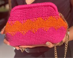 a woman holding a pink and orange purse