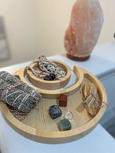 a wooden tray with various items in it on a white surface next to a large rock