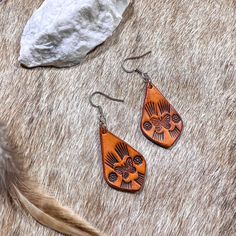 "Hand tooled earrings made from veg tanned leather and hand dyed in a soft tan color. Lightweight and flexible for all day wear.  Dimensions: 1.5\" earwire adds about .5\" to total length.  Materials: Veg tanned leather  Care: No not keep wet for long periods of time, remove before swimming or showering. Store hanging or laying flat.  Nickel and lead free ear post for sensitive ears  Each item is uniquely handcrafted and might have slight variations  Follow us on Instagram! https://www.instagram Tooled Earrings, Diy En Cuir, Veg Tan Leather, Hand Tooled Leather, Western Leather, Long Periods, Leather Diy, Sensitive Ears, Leather Care