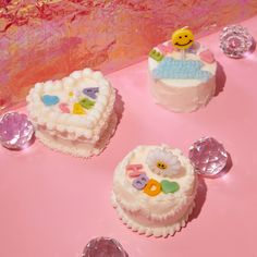 three decorated cakes sitting on top of a pink table