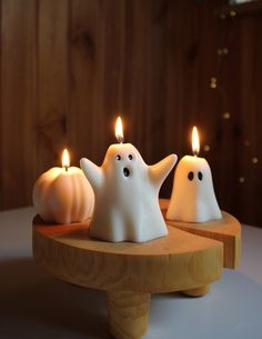 three white candles with ghost faces on them