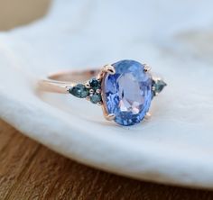 a tan and blue stone ring sitting on top of a white cloth covered tablecloth