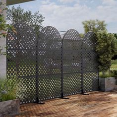 a large metal fence sitting on top of a wooden floor next to a tree and bushes