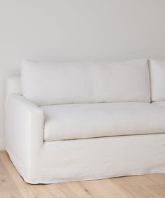 a white couch sitting on top of a hard wood floor