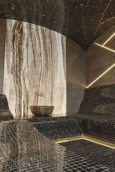 a bath room with tiled walls and a bowl on the floor in front of it