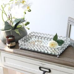 a glass tray sitting on top of a wooden table next to a vase with flowers