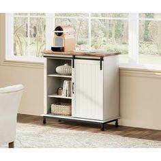 a small white cabinet with shelves and drawers in front of a window, next to a chair