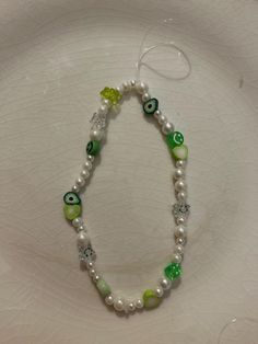 a white plate topped with a green and white beaded necklace