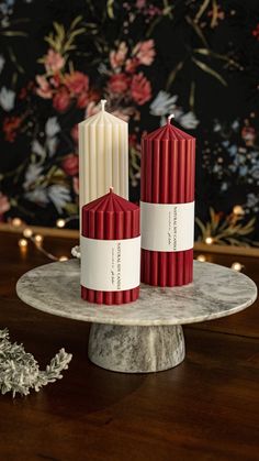 two red and white candles sitting on top of a marble plate