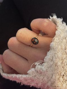 a close up of a person's hand with a ring on their finger, wearing a sweater