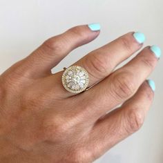 a woman's hand wearing a gold ring with a large diamond in the center