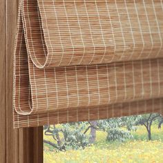 a close up of a window with blinds in the shade and yellow flowers behind it