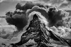 black and white photograph of a mountain peak with storm clouds in the sky above it