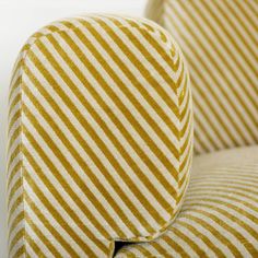 an upholstered chair with yellow and white striped fabric on it's back