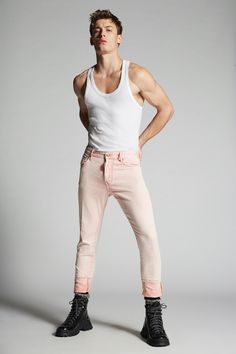 a man in white tank top and pink pants standing with his hands on his hips