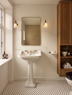 a bathroom with a toilet, sink and mirror in it's corner next to a window