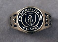 a ring with the u s army seal on it is sitting on a table in front of a gray background