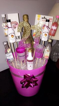 a pink bucket filled with lots of liquor bottles and candies on top of a table