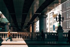 a man is walking down the street under an overpass