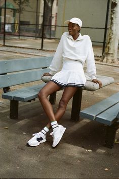 a woman sitting on top of a bench next to a tennis racquet